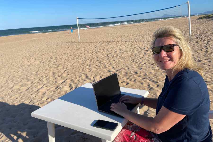 Ulrike Lang in Spanien, mit dem Laptop am Strand beim Arbeiten